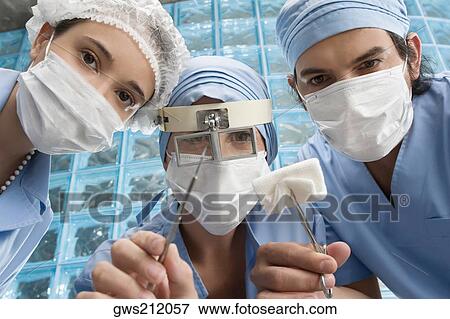 Stock Photo - Two male surgeons and a male surgeon in an operating room. Fotosearch