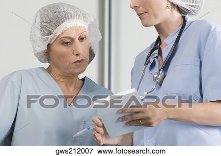 Stock Photo - Two male surgeons discussing a medical report. Fotosearch