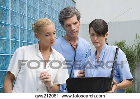 Two surgeons and a female doctor discussing a medical report View Large Photo Image Stock Image - Two surgeons and a female doctor discussing a medical report. Fotosearch