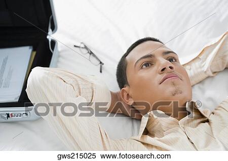 Stock Photography - Businessman lying on the bed and thinking. Fotosearch