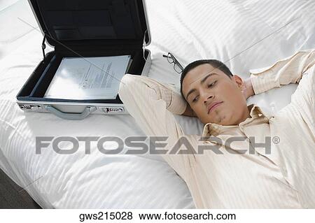 Businessman lying on the bed View Large Photo Image Stock Photo - Businessman lying on the bed. Fotosearch