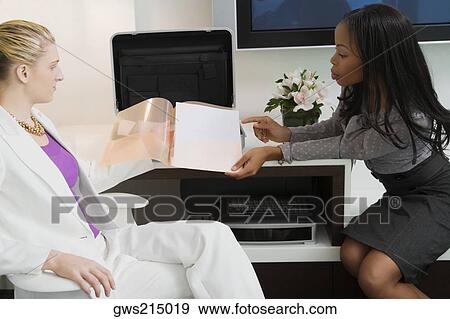 Businesswoman showing a file to another businesswoman View Large Photo Image Stock Photo - Businesswoman showing a file to another businesswoman. Fotosearch