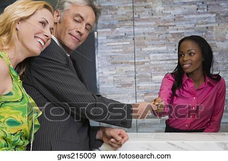 Mature man giving a credit card to a hotel receptionist View Large Photo Image Stock Photo - Mature man giving a credit card to a hotel receptionist. Fotosearch