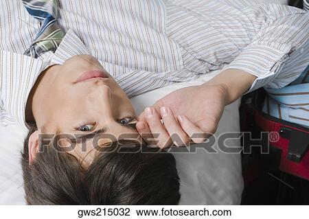 Stock Image - Portrait of a businessman lying on the bed. Fotosearch