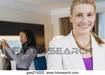 Portrait of a businesswoman smiling with another businesswoman standing in the background View Large Photo Image Stock Image - Portrait of a businesswoman smiling with another businesswoman standing in the background. Fotosearch