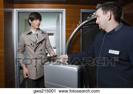Room service man handing over a briefcase to a businessman View Large Photo Image Stock Image - Room service man handing over a briefcase to a businessman. Fotosearch