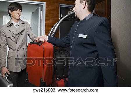 Room service man handing over luggage to a businessman View Large Photo Image Stock Image - Room service man handing over luggage to a businessman. Fotosearch