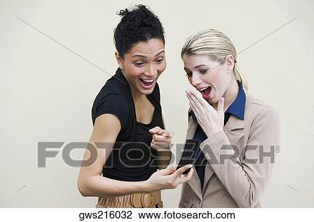 Close-up of two young women looking at a mobile phone View Large Photo Image Stock Image - Close-up of two young women looking at a mobile phone. Fotosearch