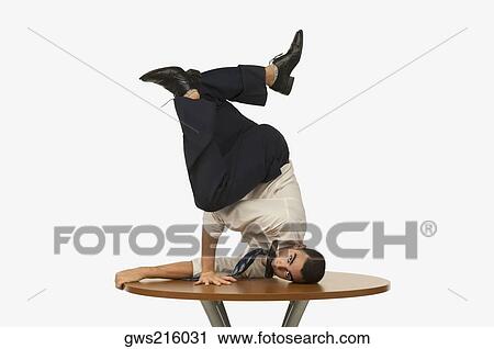 Portrait of a businessman doing a handstand on a table with a mobile phone in his mouth View Large Photo Image Stock Image - Portrait of a businessman doing a handstand on a table with a mobile phone in his mouth. Fotosearch