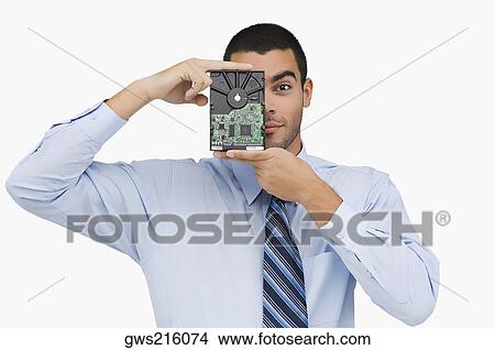 Portrait of a businessman holding a hard drive in front of his face View Large Photo Image Picture - Portrait of a businessman holding a hard drive in front of his face. Fotosearch