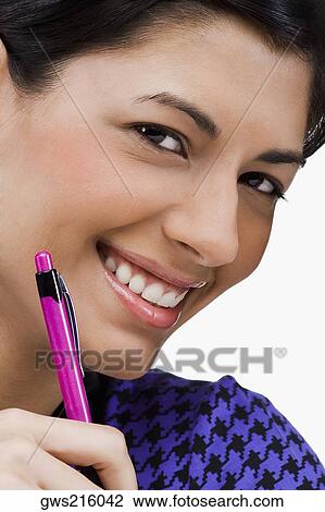 Portrait of a young woman holding a pen and smiling View Large Photo Image Stock Image - Portrait of a young woman holding a pen and smiling. Fotosearch