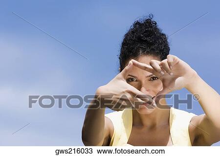 Portrait of a young woman making a finger frame and smiling View Large Photo Image Stock Image - Portrait of a young woman making a finger frame and smiling. Fotosearch