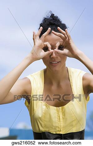 Stock Image - Portrait of a young woman pretending to wear eyeglasses. Fotosearch