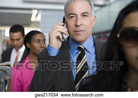 Businessman talking on a mobile phone at an airport View Large Photo Image Picture - Businessman talking on a mobile phone at an airport. Fotosearch