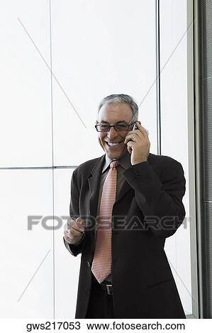 Businessman talking on a mobile phone and smiling in the waiting room of an airport View Large Photo Image Stock Image - Businessman talking on a mobile phone and smiling in the waiting room of an airport. Fotosearch