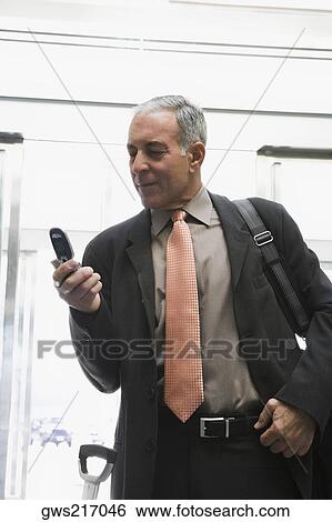 Stock Photograph - Businessman using a mobile phone in the waiting room of an airport. Fotosearch