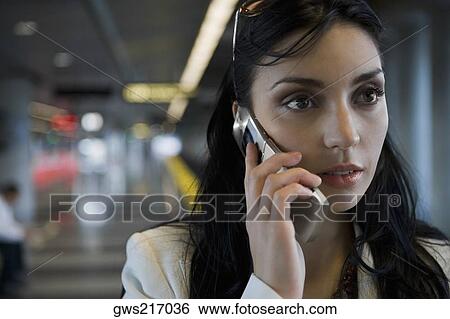 Close-up of a young woman talking on a mobile phone at a subway station View Large Photo Image Stock Photograph - Close-up of a young woman talking on a mobile phone at a subway station. Fotosearch