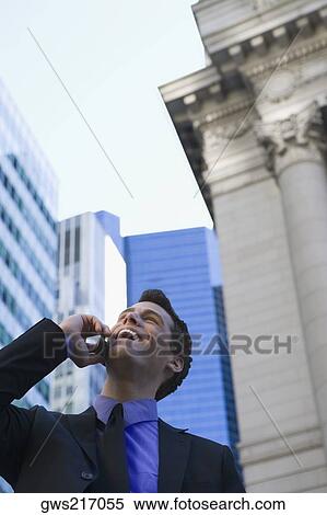 Low angle view of a businessman talking on a mobile phone and laughing View Large Photo Image Stock Photography - Low angle view of a businessman talking on a mobile phone and laughing. Fotosearch