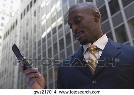 Low angle view of a businessman using a mobile phone View Large Photo Image Picture - Low angle view of a businessman using a mobile phone. Fotosearch