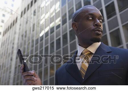 Stock Photography - Low angle view of a businessman using a mobile phone. Fotosearch