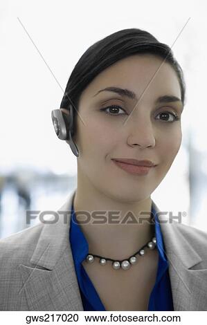 Stock Image - Portrait of a businesswoman wearing a hands free device and smiling. Fotosearch