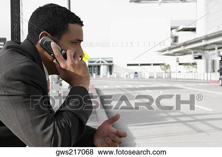 Stock Photo - Side profile of a businessman talking on a mobile phone. Fotosearch