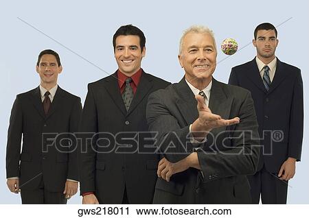Businessman catching a rubber band ball with three businessmen standing behind him View Large Photo Image Stock Image - Businessman catching a rubber band ball with three businessmen standing behind him. Fotosearch