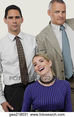 Stock Image - Close-up of a businesswoman laughing with two businessmen standing behind her. Fotosearch