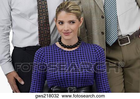 Close-up of a businesswoman smiling with two businessmen standing behind her View Large Photo Image Stock Image - Close-up of a businesswoman smiling with two businessmen standing behind her. Fotosearch