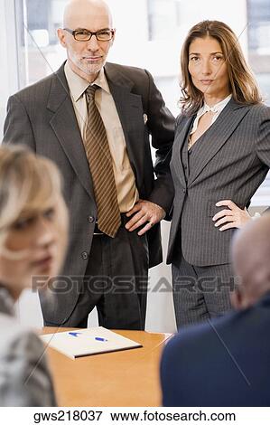 Portrait of a businessman and a businesswoman standing in front of their colleagues View Large Photo Image Stock Photo - Portrait of a businessman and a businesswoman standing in front of their colleagues. Fotosearch