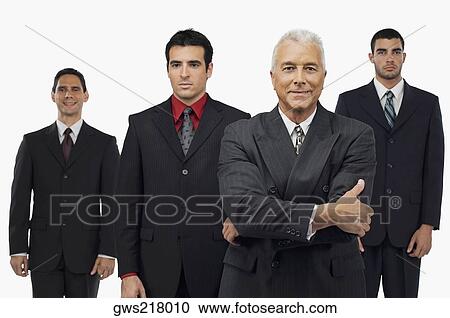 Stock Image - Portrait of a businessman smiling with three businessmen standing behind him. Fotosearch