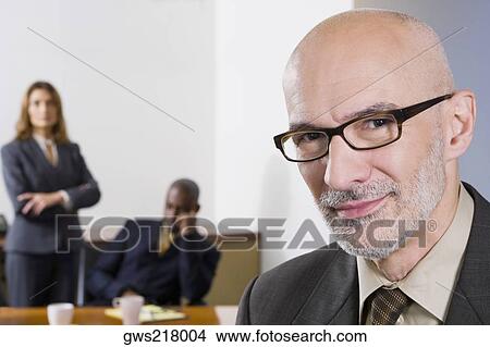 Portrait of a businessman with his colleagues in the background View Large Photo Image Picture - Portrait of a businessman with his colleagues in the background. Fotosearch