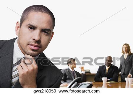 Portrait of a businessman with his colleagues discussing in the background View Large Photo Image Stock Image - Portrait of a businessman with his colleagues discussing in the background. Fotosearch