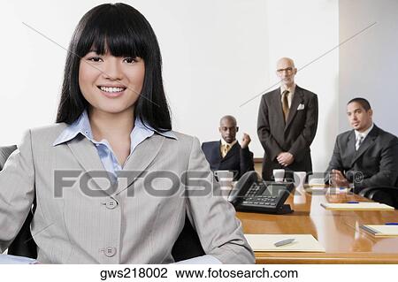 Portrait of a businesswoman smiling with her colleagues in the background View Large Photo Image Stock Image - Portrait of a businesswoman smiling with her colleagues in the background. Fotosearch