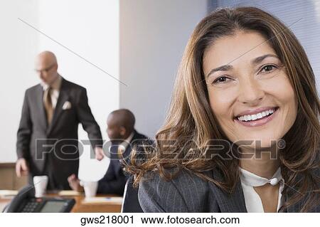 Stock Image - Portrait of a businesswoman with her colleagues in the background. Fotosearch
