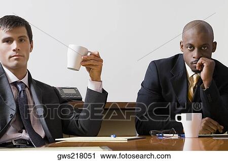 Portrait of two businessmen sitting in a board room View Large Photo Image Stock Image - Portrait of two businessmen sitting in a board room. Fotosearch
