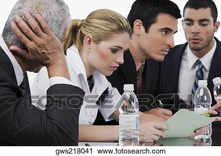 Stock Image - Three businessmen and a businesswoman at a meeting in a conference room. Fotosearch