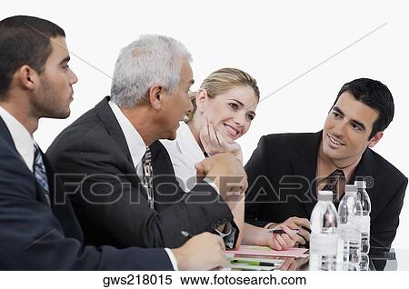 Stock Photography - Three businessmen and a businesswoman at a meeting in a conference room. Fotosearch