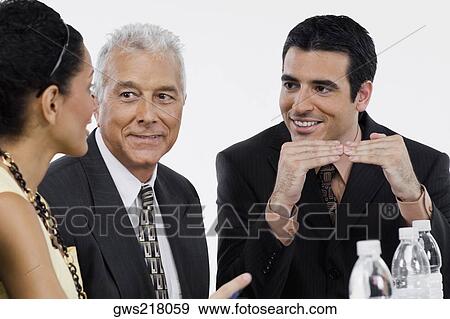 Two businessmen and a businesswoman at a meeting in a conference room View Large Photo Image Stock Photo - Two businessmen and a businesswoman at a meeting in a conference room. Fotosearch