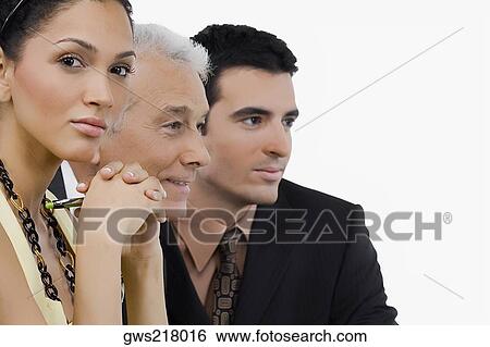 Stock Photograph - Two businessmen and a businesswoman at a meeting in a conference room. Fotosearch
