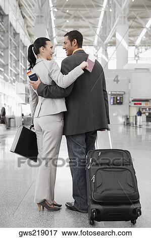 Businessman and a businesswoman standing at an airport with their arms around each other View Large Photo Image Stock Photo - Businessman and a businesswoman standing at an airport with their arms around each other . Fotosearch
