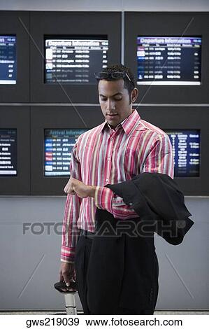 Businessman checking the time at an airport View Large Photo Image Stock Photo - Businessman checking the time at an airport. Fotosearch