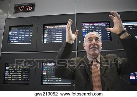 Businessman looking angry in front of an arrival departure board at an airport View Large Photo Image Stock Image - Businessman looking angry in front of an arrival departure board at an airport. Fotosearch