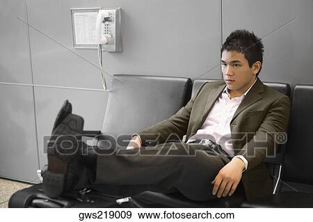 Stock Photo - Businessman reclining on a bench at an airport. Fotosearch