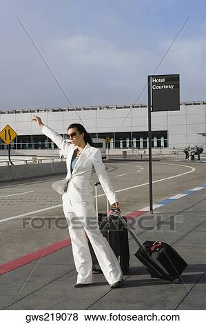 Businesswoman hailing a taxi outside an airport View Large Photo Image Stock Photo - Businesswoman hailing a taxi outside an airport. Fotosearch