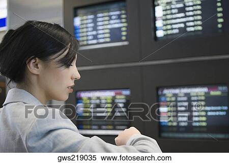Stock Photography - Close-up of a businesswoman checking the time at an airport. Fotosearch