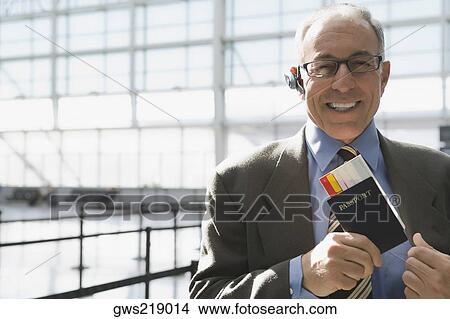 Picture - Portrait of a businessman putting a passport with an airplane ticket in his coat's pocket. Fotosearch