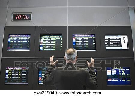 Rear view of a businessman standing with his arms raised in front of an arrival departure board at an airport View Large Photo Image Stock Photo - Rear view of a businessman standing with his arms raised in front of an arrival departure board at an airport. Fotosearch