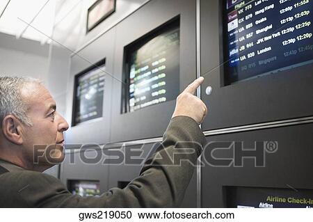 Side profile of a businessman pointing at an arrival departure board in an airport View Large Photo Image Stock Image - Side profile of a businessman pointing at an arrival departure board in an airport. Fotosearch