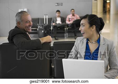 Side profile of a businessman with a businesswoman looking at each other and smiling at an airport View Large Photo Image Stock Image - Side profile of a businessman with a businesswoman looking at each other and smiling at an airport. Fotosearch